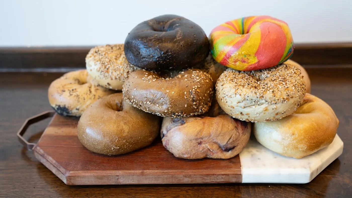 A stack of assorted fresh bagels on a wood board