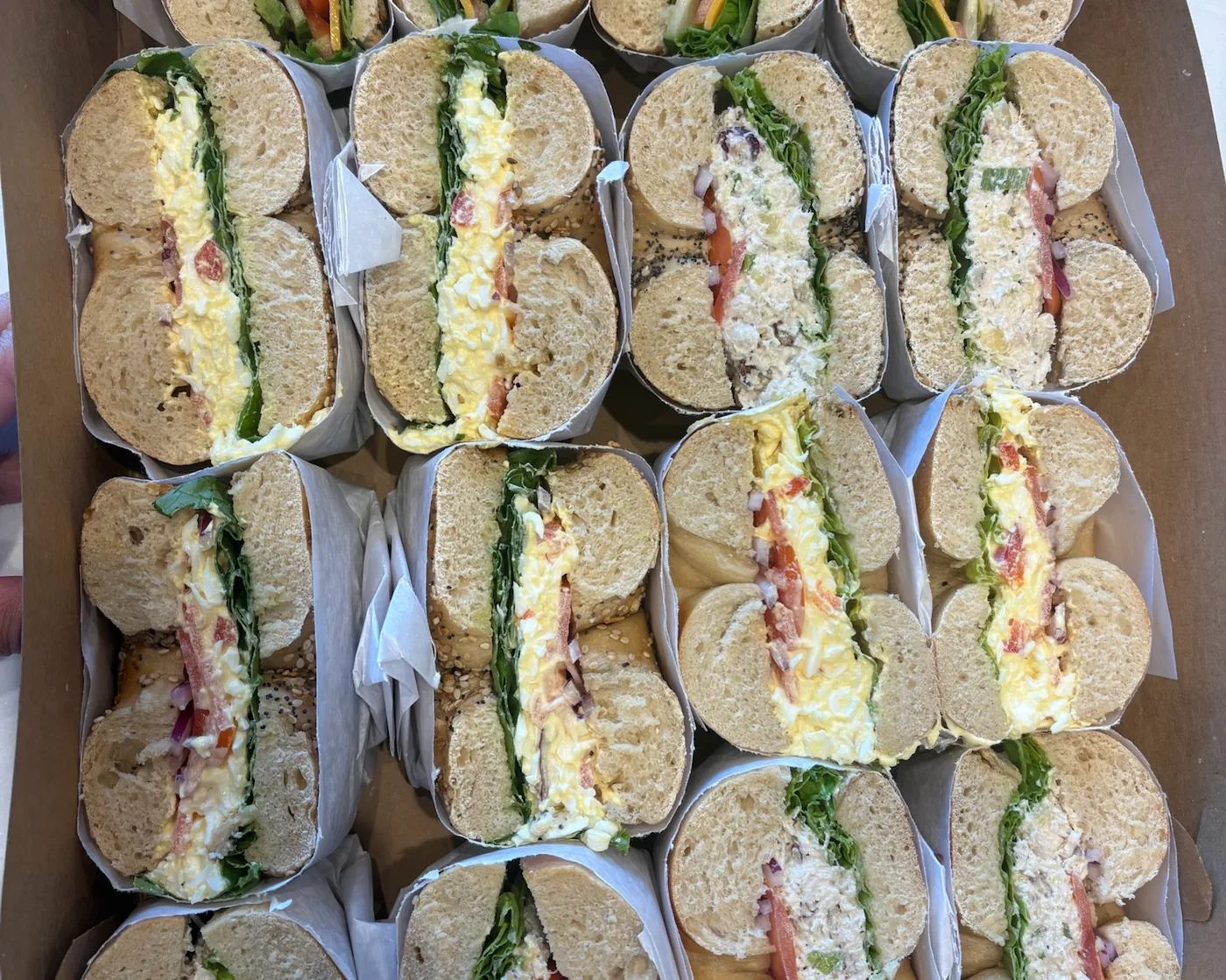 A catering tray of B's Bagels bagel sandwiches cut and boxed for an office lunch